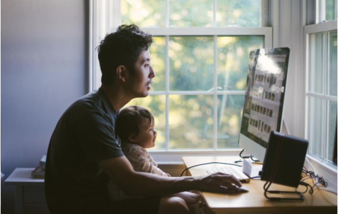 Picture of asian man with child in his lap typing on his computer.